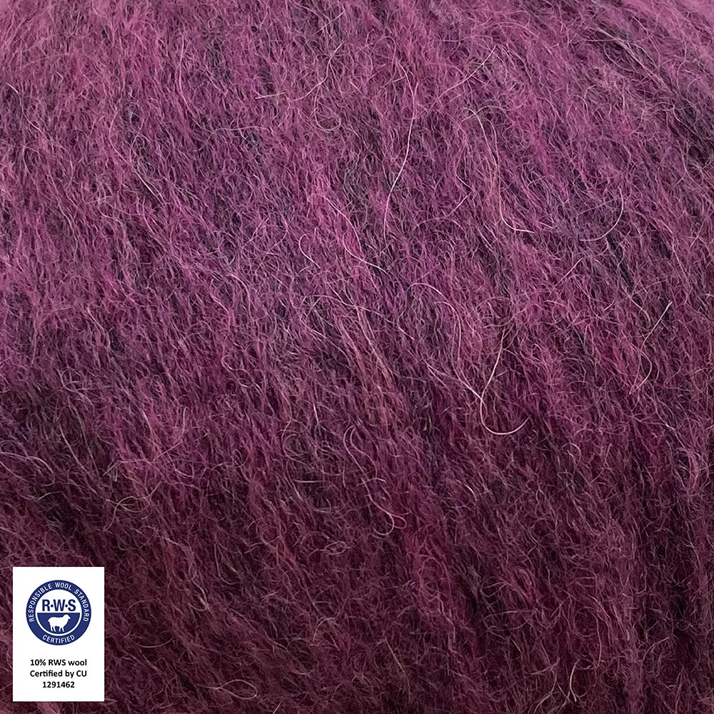 Close-up van een bol Snefnug-garen in een pruim  kleur. Dit lichte blowyarn heeft een kern van katoen met ingeblazen alpaca- en merinovezels, wat zorgt voor een luchtige, pluizige structuur. Onderaan zijn de RAS- en RWS-certificeringslogo's zichtbaar.