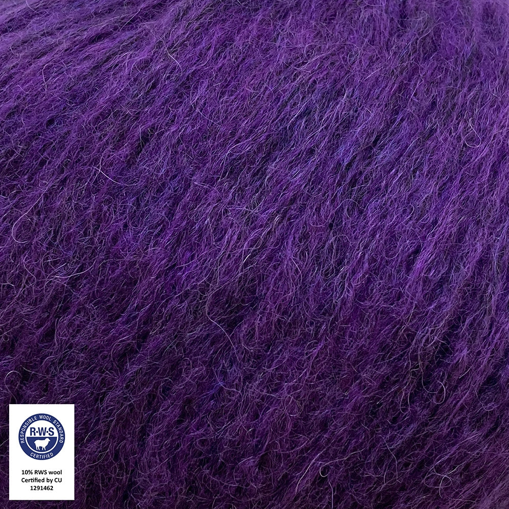 Close-up van een bol Snefnug-garen in een helder paarse kleur. Dit lichte blowyarn heeft een kern van katoen met ingeblazen alpaca- en merinovezels, wat zorgt voor een luchtige, pluizige structuur. Onderaan zijn de RAS- en RWS-certificeringslogo's zichtbaar.