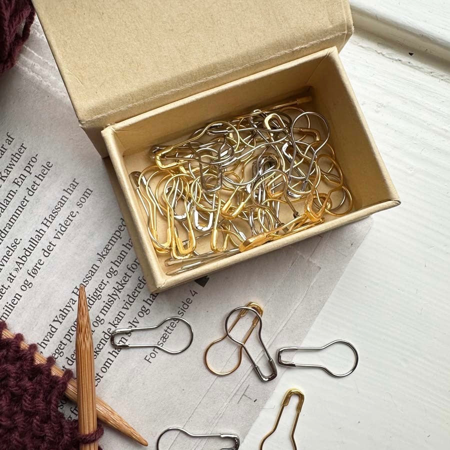 Kartonnen doosje met magneet sluiting gevuld met opening stitch markers van PetiteKnit