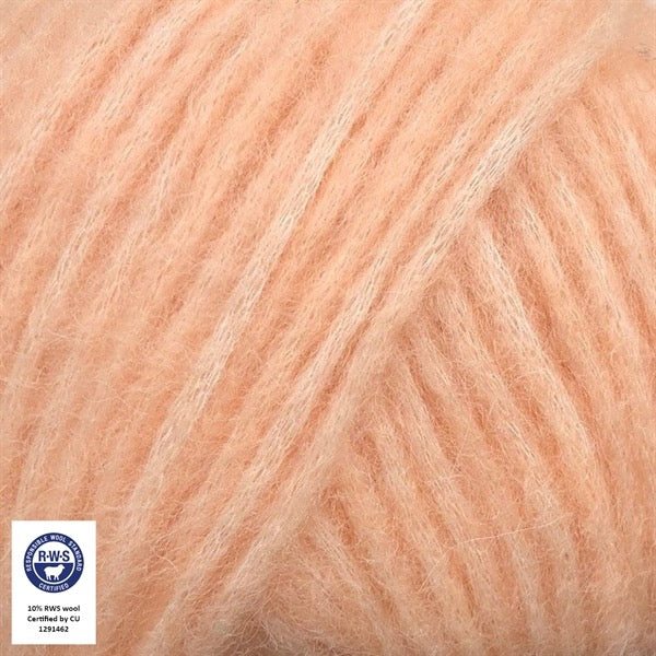Close-up van een bol Snefnug-garen in een zachte, perzik kleur. Dit lichte blowyarn heeft een kern van katoen met ingeblazen alpaca- en merinovezels, wat zorgt voor een luchtige, pluizige structuur. Onderaan zijn de RAS- en RWS-certificeringslogo's zichtbaar.
