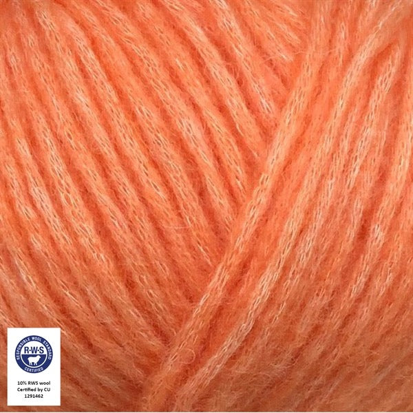 Close-up van een bol Snefnug-garen in een koraal oranje kleur. Dit lichte blowyarn heeft een kern van katoen met ingeblazen alpaca- en merinovezels, wat zorgt voor een luchtige, pluizige structuur. Onderaan zijn de RAS- en RWS-certificeringslogo's zichtbaar.