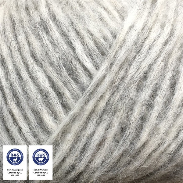 Close-up van een bol Snefnug-garen in een zachte, lichtgrijze kleur. Dit lichte blowyarn heeft een kern van katoen met ingeblazen alpaca- en merinovezels, wat zorgt voor een luchtige, pluizige structuur. Onderaan zijn de RAS- en RWS-certificeringslogo's zichtbaar.
