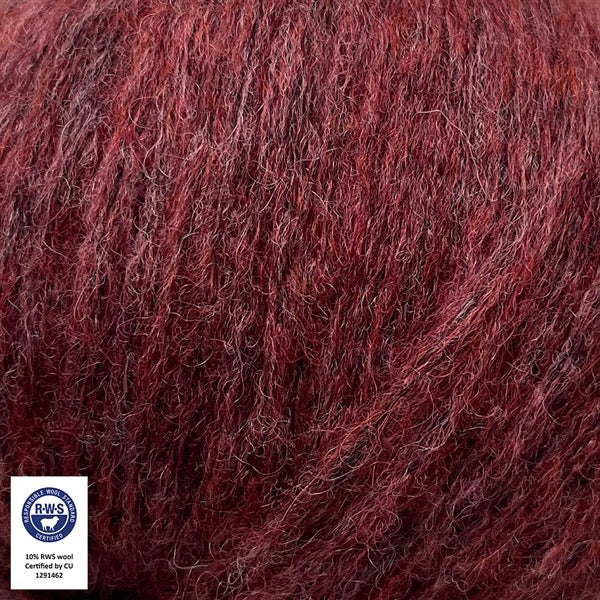 Close-up van een bol Snefnug-garen in een zachte, gedempte bordeaux kleur. Dit lichte blowyarn heeft een kern van katoen met ingeblazen alpaca- en merinovezels, wat zorgt voor een luchtige, pluizige structuur. Onderaan zijn de RAS- en RWS-certificeringslogo's zichtbaar.