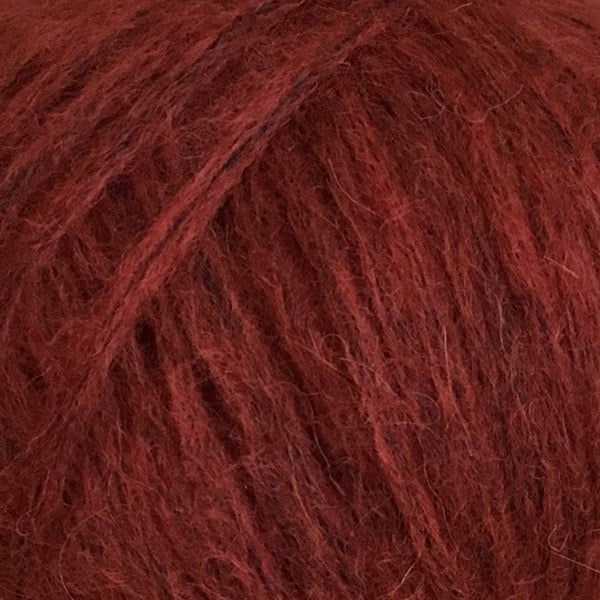 Close-up van een bol Snefnug-garen in een burnt orange kleur. Dit lichte blowyarn heeft een kern van katoen met ingeblazen alpaca- en merinovezels, wat zorgt voor een luchtige, pluizige structuur. Onderaan zijn de RAS- en RWS-certificeringslogo's zichtbaar.
