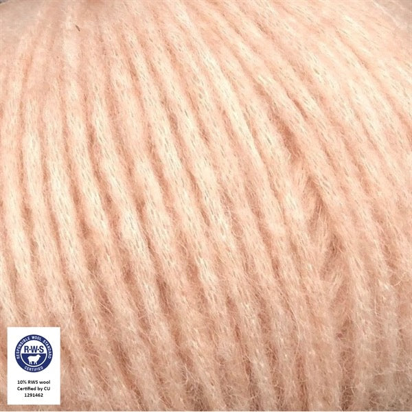 Close-up van een bol Snefnug-garen in een zachte, licht poederige perzik kleur. Dit lichte blowyarn heeft een kern van katoen met ingeblazen alpaca- en merinovezels, wat zorgt voor een luchtige, pluizige structuur. Onderaan zijn de RAS- en RWS-certificeringslogo's zichtbaar.