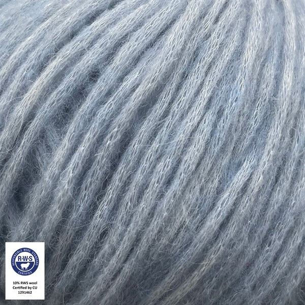 Close-up van een bol Snefnug-garen in een Lysduebla kleur. Dit lichte blowyarn heeft een kern van katoen met ingeblazen alpaca- en merinovezels, wat zorgt voor een luchtige, pluizige structuur. Onderaan zijn de RAS- en RWS-certificeringslogo's zichtbaar.