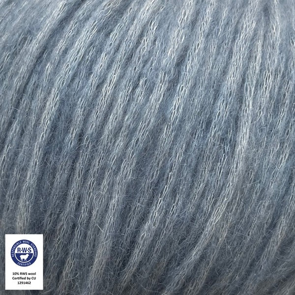 Close-up van een bol Snefnug-garen in een zachte, poederig blauwe kleur. Dit lichte blowyarn heeft een kern van katoen met ingeblazen alpaca- en merinovezels, wat zorgt voor een luchtige, pluizige structuur. Onderaan zijn de RAS- en RWS-certificeringslogo's zichtbaar.