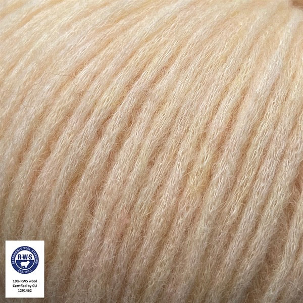 Close-up van een bol Snefnug-garen in een zachte,vanille kleur. Dit lichte blowyarn heeft een kern van katoen met ingeblazen alpaca- en merinovezels, wat zorgt voor een luchtige, pluizige structuur. Onderaan zijn de RAS- en RWS-certificeringslogo's zichtbaar.