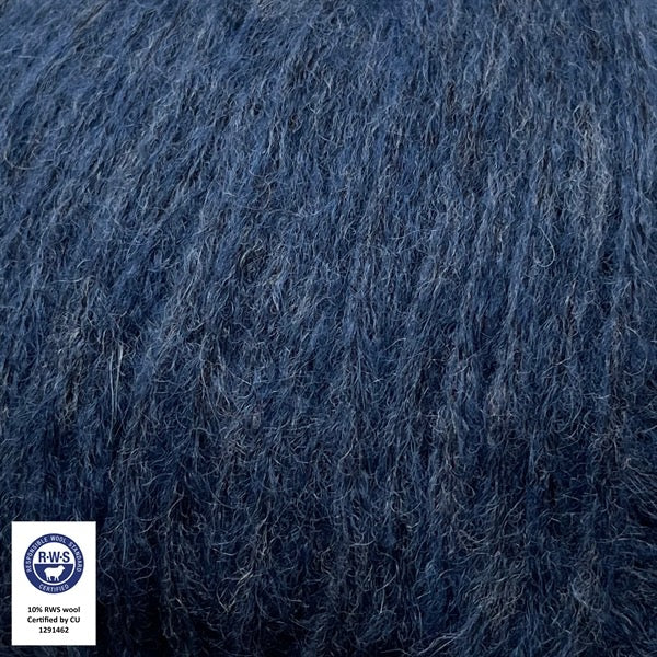 Close-up van een bol Snefnug-garen in een  midnatsbla kleur. Dit lichte blowyarn heeft een kern van katoen met ingeblazen alpaca- en merinovezels, wat zorgt voor een luchtige, pluizige structuur. Onderaan zijn de RAS- en RWS-certificeringslogo's zichtbaar
