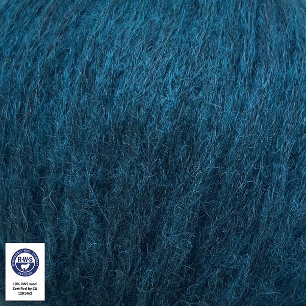 Close-up van een bol Snefnug-garen in een Teal kleur. Dit lichte blowyarn heeft een kern van katoen met ingeblazen alpaca- en merinovezels, wat zorgt voor een luchtige, pluizige structuur. Onderaan zijn de RAS- en RWS-certificeringslogo's zichtbaar.
