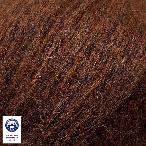 Close-up van een bol Snefnug-garen in een warme koffie bruine kleur. Dit lichte blowyarn heeft een kern van katoen met ingeblazen alpaca- en merinovezels, wat zorgt voor een luchtige, pluizige structuur. Onderaan zijn de RAS- en RWS-certificeringslogo's zichtbaar.