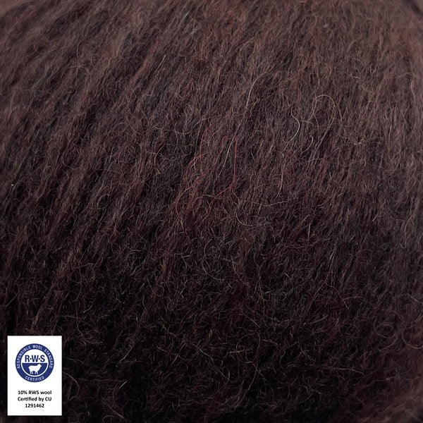 Close-up van een bol Snefnug-garen in een mahonie bruine kleur. Dit lichte blowyarn heeft een kern van katoen met ingeblazen alpaca- en merinovezels, wat zorgt voor een luchtige, pluizige structuur. Onderaan zijn de RAS- en RWS-certificeringslogo's zichtbaar.