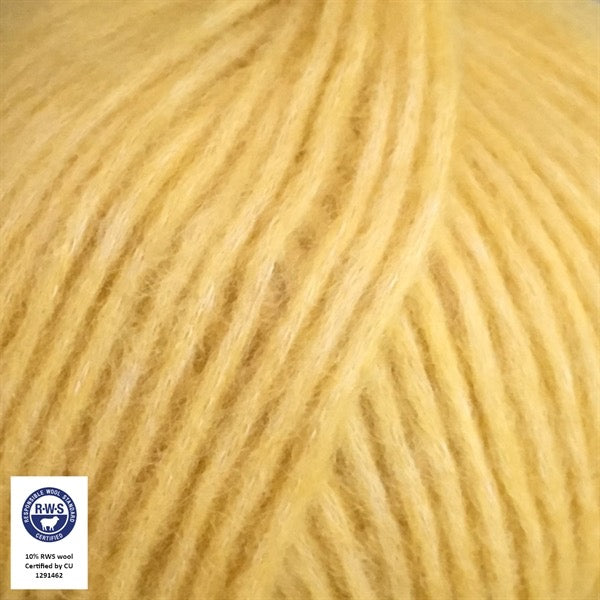 Close-up van een bol Snefnug-garen in een zachte, citroengele kleur. Dit lichte blowyarn heeft een kern van katoen met ingeblazen alpaca- en merinovezels, wat zorgt voor een luchtige, pluizige structuur. Onderaan zijn de RAS- en RWS-certificeringslogo's zichtbaar.