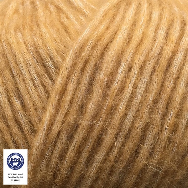Close-up van een bol Snefnug-garen in een goudgele kleur. Dit lichte blowyarn heeft een kern van katoen met ingeblazen alpaca- en merinovezels, wat zorgt voor een luchtige, pluizige structuur. Onderaan zijn de RAS- en RWS-certificeringslogo's zichtbaar.