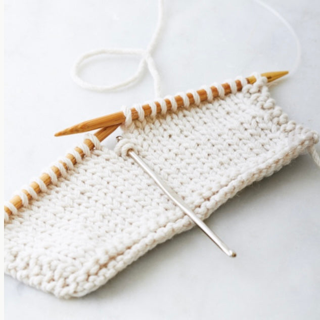 Een breiwerk waar met een stitch fixer een steek wordt opgehaald 