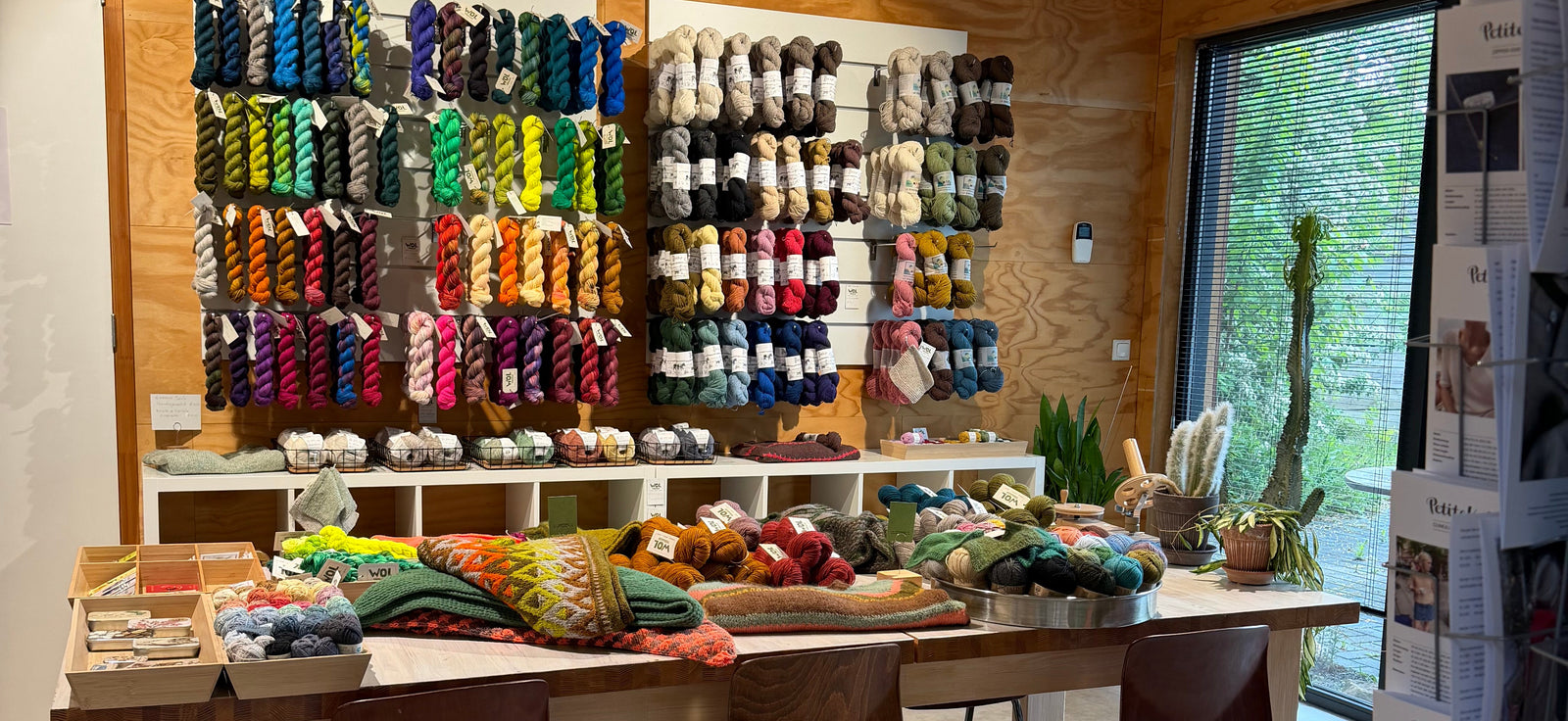 Een hoek van de winkel in Tynaarlo met een wand vol met handgeverfde garens en een grote tafel om aan te breien