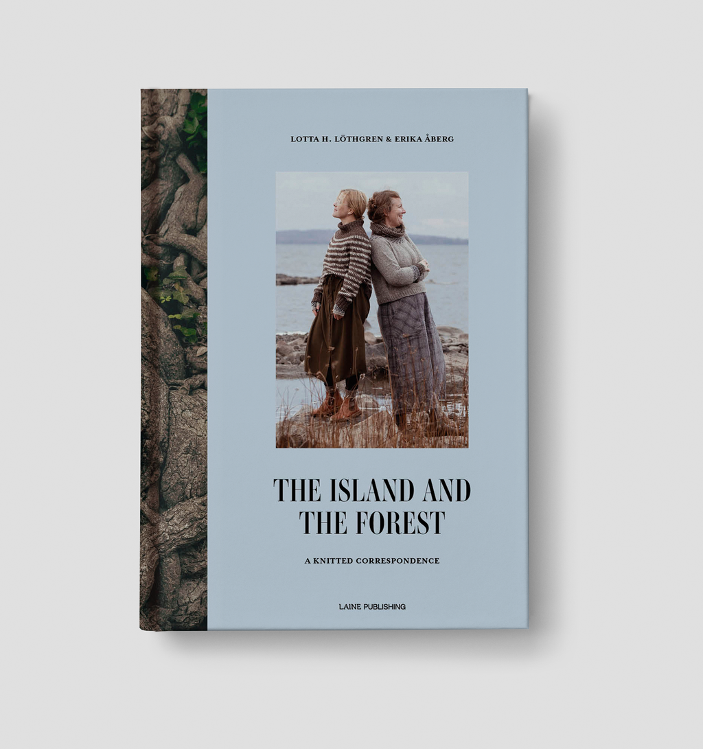 Boekomslag van "The Island and the Forest – A Knitted Correspondence" door Lotta H. Löthgren en Erika Åberg. Op de lichtblauwe omslag staan twee vrouwen rug aan rug aan een rotsachtige kust, gekleed in handgebreide truien en rokken. Uitgegeven door Laine Publishing.